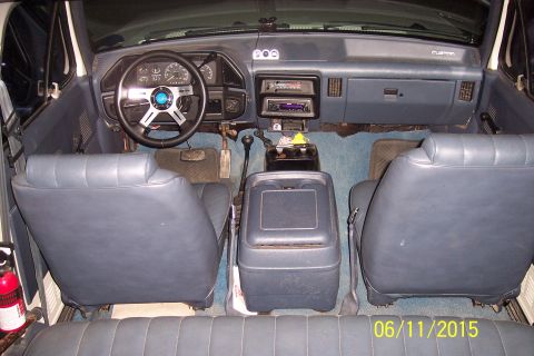 1990 Ford Bronco - The interior of a vehicle, likely a Ford Bronco, shows a blue interior with two front bucket seats, a center console with a gear shifter, a…