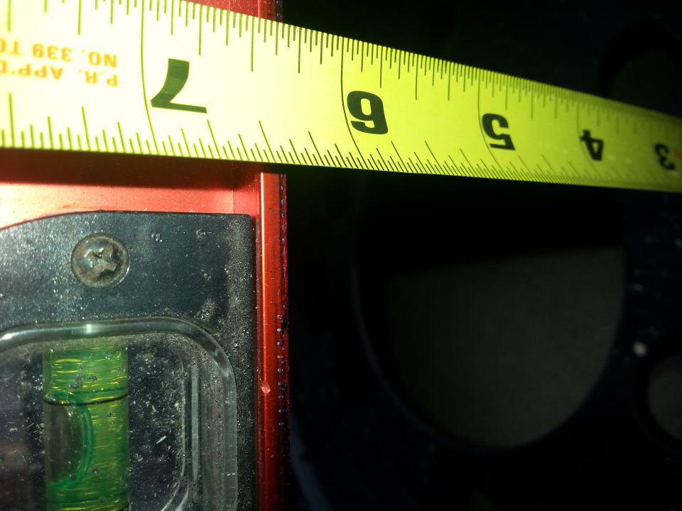 Yellow measuring tape showing inches over a red and black object.