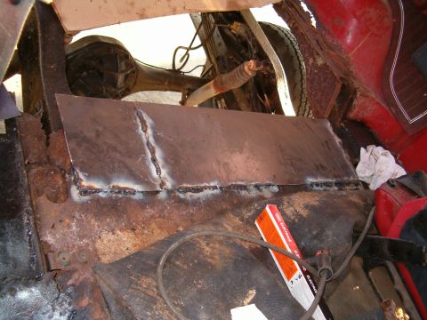 1979 Ford Bronco - A metal patch is being welded into a heavily rusted vehicle floor pan, with the rear axle and suspension components visible.