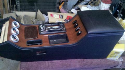 1982 Ford Bronco - A custom car center console with wood grain trim, a chrome shifter, three gauges, and several toggle switches is shown. The console is upho…