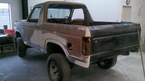 1982 Ford Bronco - The rear passenger side of a classic Ford Bronco undergoing restoration is shown. The vehicle has a brown and black two-tone paint scheme w…