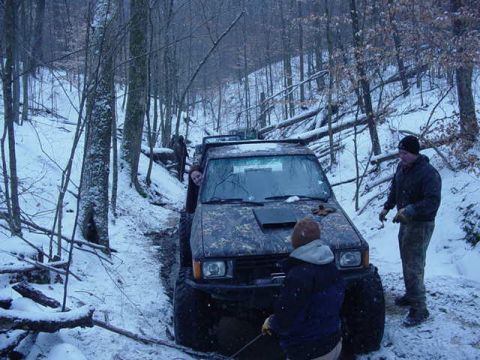 1992 Ford Bronco - A group navigates a snowy, wooded trail in a modified off-road vehicle.