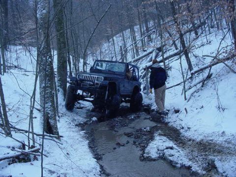 1992 Ford Bronco - A Jeep Wrangler navigates a challenging off-road trail during winter conditions.