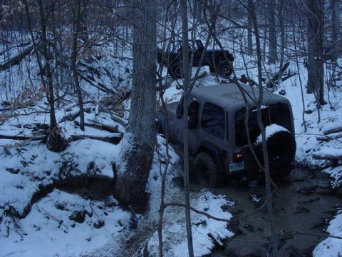 1992 Ford Bronco - Two Jeeps are stuck in mud and snow on a wooded trail.
