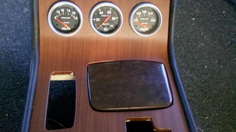 1982 Ford Bronco - A close-up view of a wooden dashboard with three gauges: Volts, Oil, and Water temperature. There are also two cutouts for what appear to b…