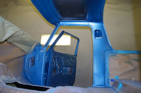1979 Ford Bronco - The interior of a classic pickup truck cab is shown, with the driver's side door open and both the door and cab frame painted in a metallic…
