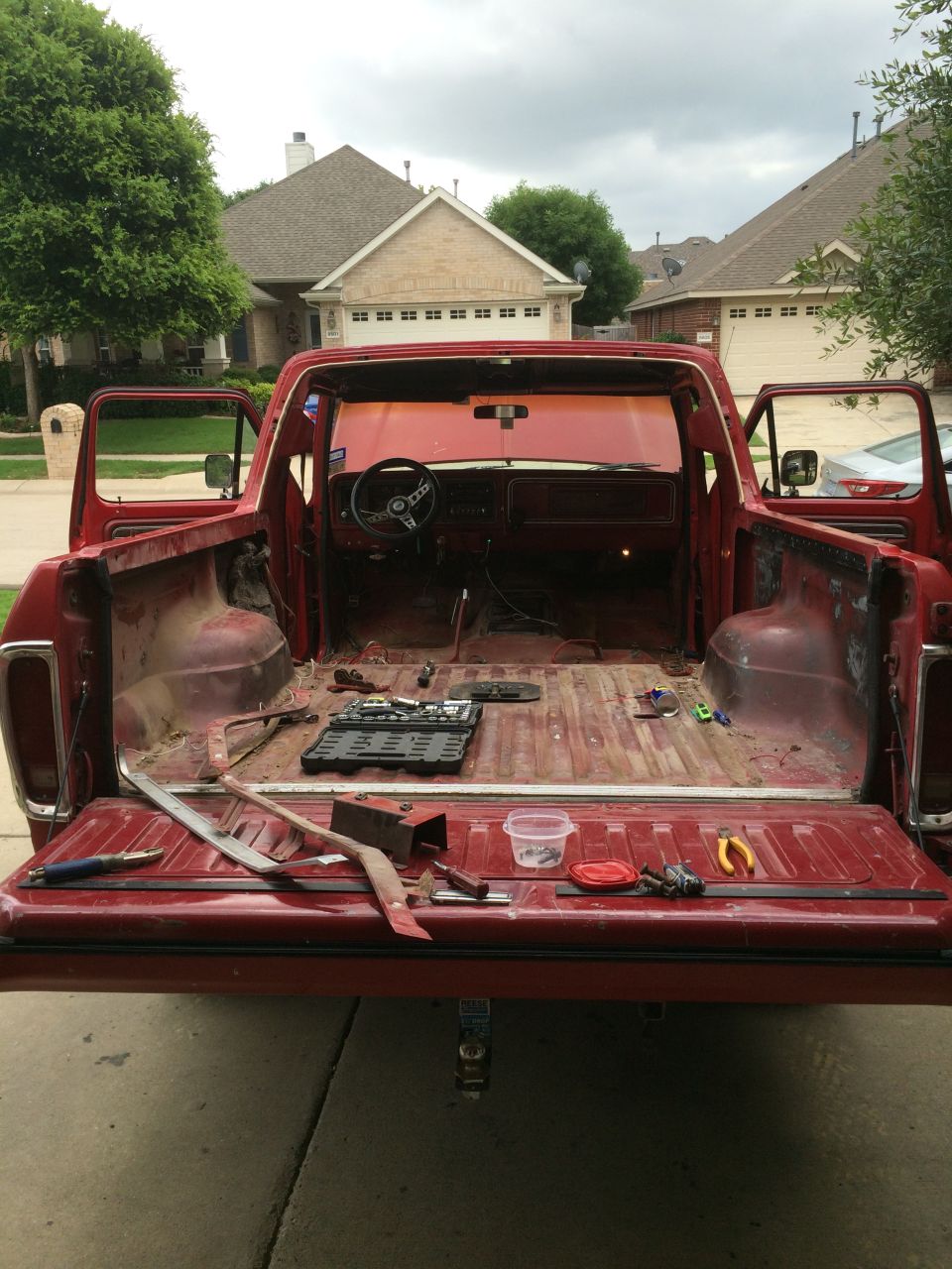 Red pickup truck with doors and tailgate open, interior stripped, tools on bed floor
