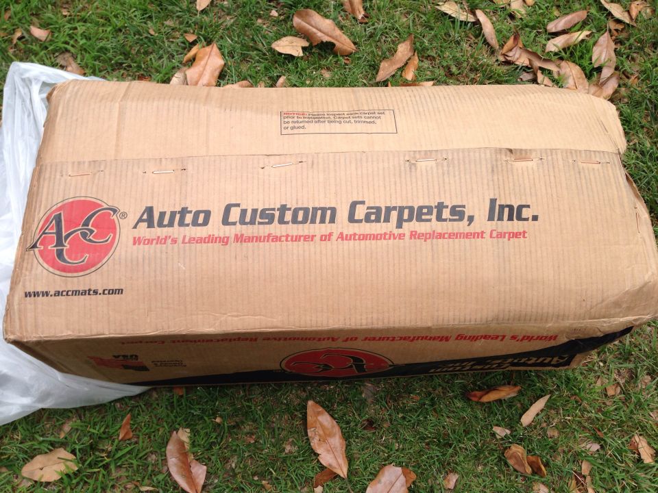 Cardboard box from Auto Custom Carpets, Inc. on grass.