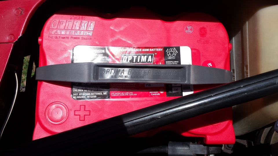 Red Optima Batteries AGM battery with black carrying strap.