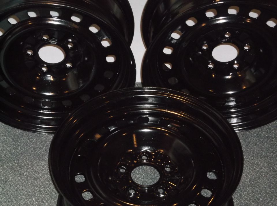 Four black steel wheels on a gray carpet.