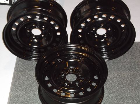 1999 Mercury Grand Marquis - Three black steel wheels are shown, with one in the foreground and two behind it. The wheels have a multi-hole design around the center hub.