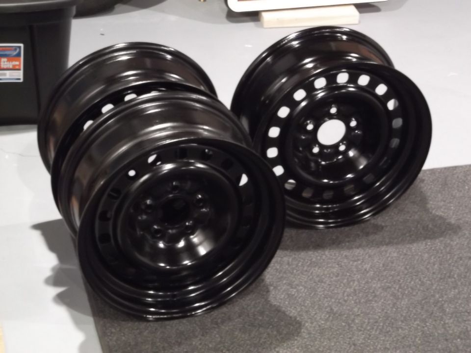 Two black steel wheels stacked on a gray carpeted surface.