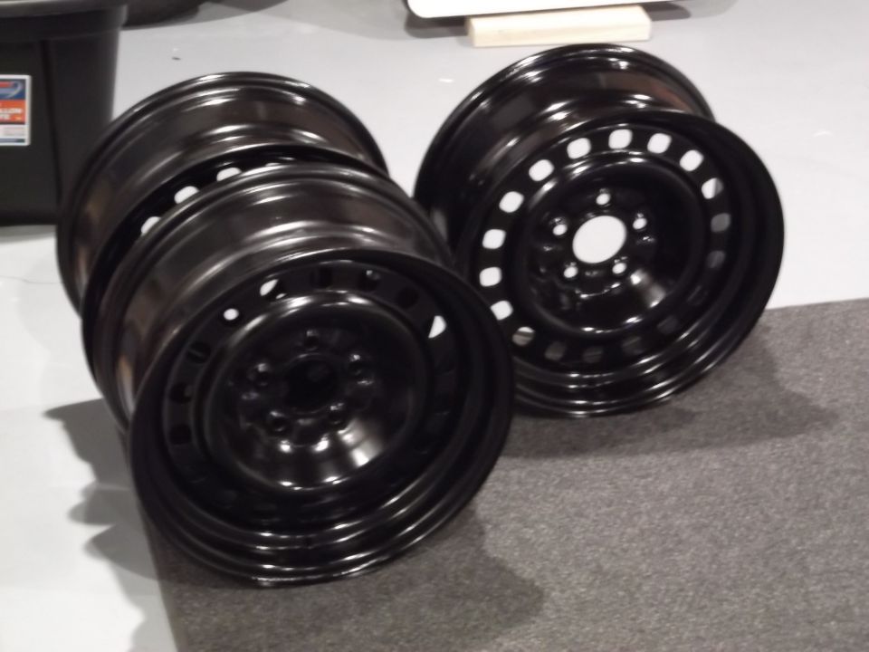 Two black steel wheels stacked on a gray carpet