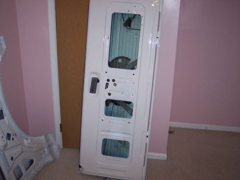 1990 Ford Bronco - A white car door, likely for a van or SUV, is shown indoors.
