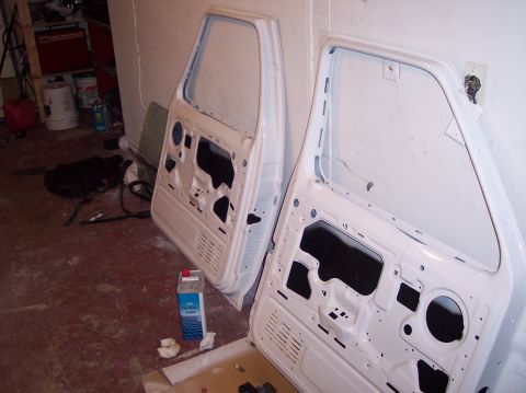 1990 Ford Bronco - Two white vehicle doors are shown disassembled and leaning against a wall in a garage setting.