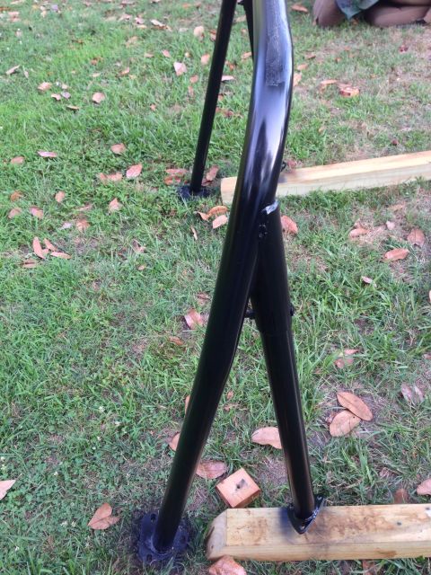 1979 Ford Bronco - A black metal frame is shown outdoors, resting on grass and wooden blocks.
