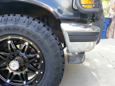 1994 Ford Bronco - Close-up of a black 1992 Ford Bronco's front wheel and chrome bumper with black trim.