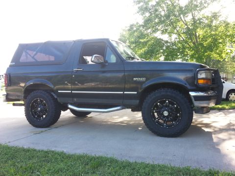 1994 Ford Bronco - This Ford Bronco is shown from the side, a soft top and custom wheels.