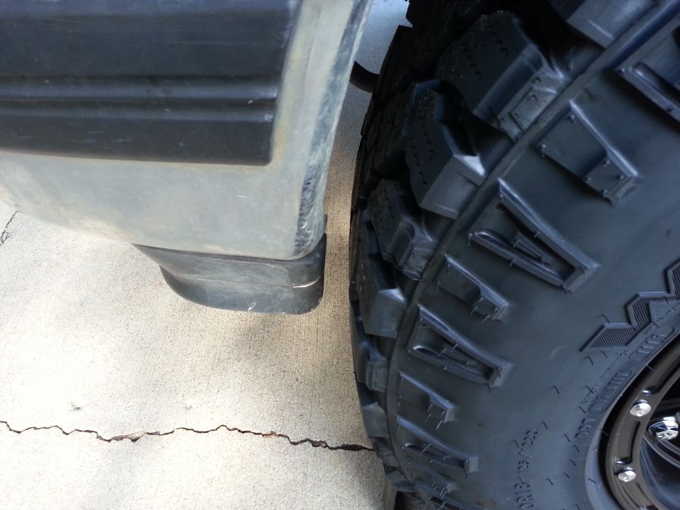 Close-up of a large, knobby tire next to a gray fender flare with black trim