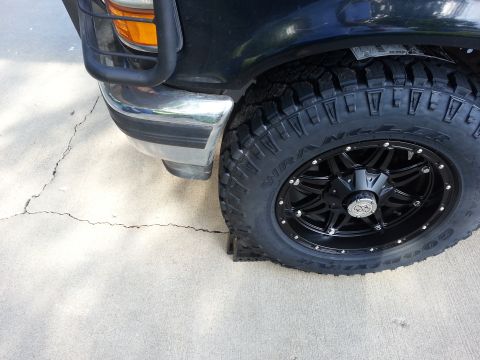 1994 Ford Bronco - Close-up of the front wheel and fender of a black 1994 Ford Bronco, a chrome bumper and grille guard.