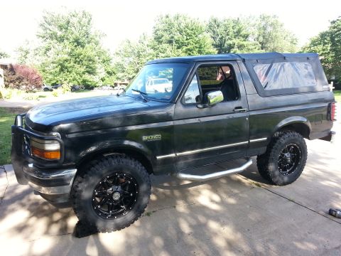1994 Ford Bronco - This black Ford Bronco has a removable soft top and aftermarket wheels.