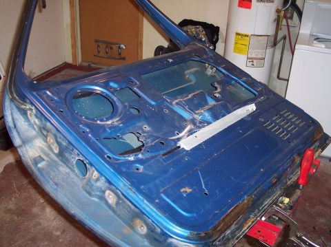 1990 Ford Bronco - A stripped-down blue car door is shown in a garage setting, with household appliances visible in the background.