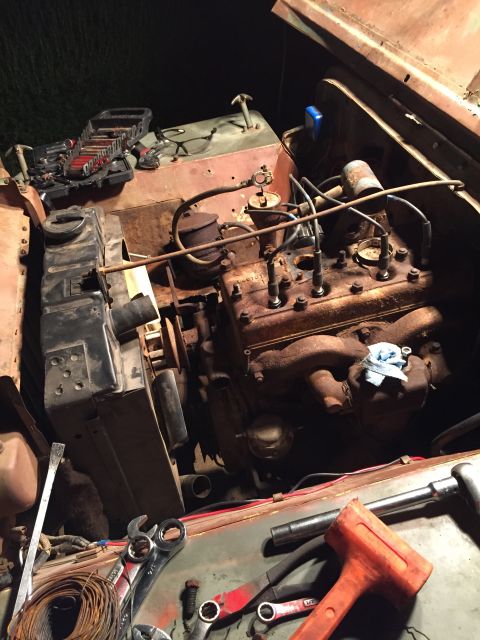 1946 Jeep Willys - Tools and parts are laid out around the engine of a vehicle, suggesting ongoing maintenance or repair.