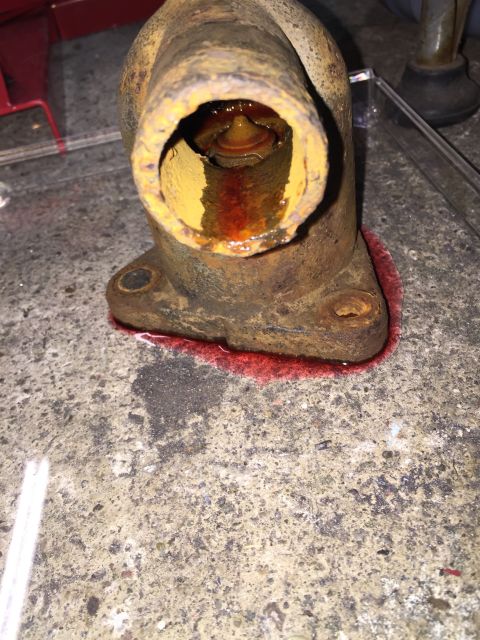 1946 Jeep Willys - A corroded thermostat housing shows signs of a red fluid leak, indicating a potential cooling system issue.