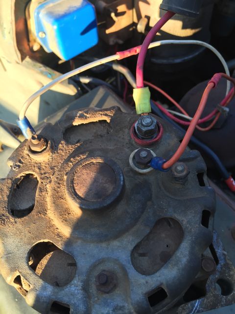 1946 Jeep Willys - The wiring on this automotive alternator is connected to a blue voltage regulator. The alternator itself is dusty and appears worn.