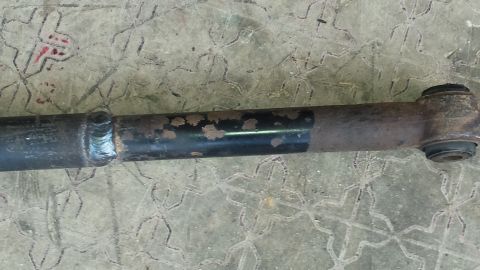 Rusty suspension part with a weld and rubber bushing, on a textured surface