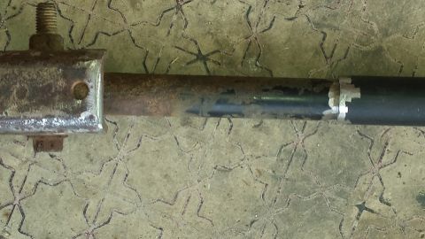 Metal rod with bolt and white tape on a patterned surface
