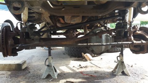 Undercarriage of a vehicle on jack stands, showing suspension and steering components