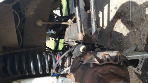 Close-up of vehicle suspension with coil spring, shock absorber, and brake rotor