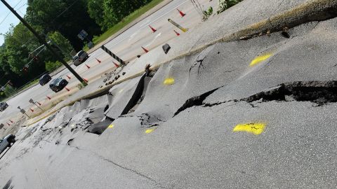 1979 Ford Bronco - A significant road collapse creates a hazardous scene with traffic cones and vehicles navigating the damaged area.