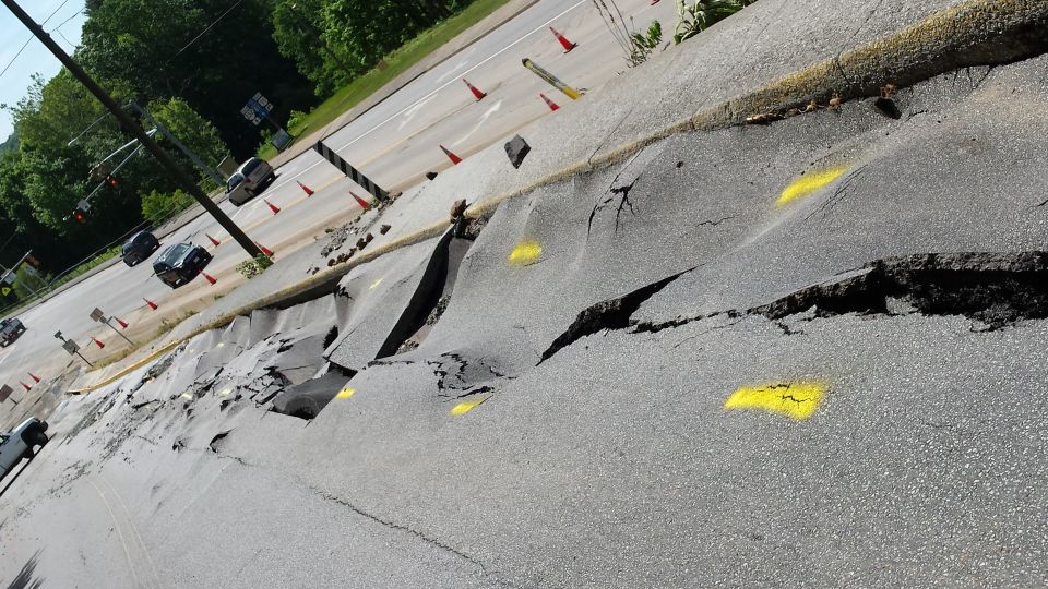 Road collapse with traffic cones and vehicles on highway