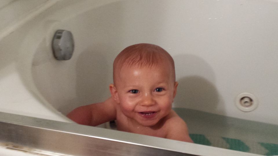 Baby smiling in a bathtub with a "Supermotors.net" logo visible