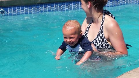 1979 Ford Bronco - A baby enjoys a swim in the pool with assistance from a woman.