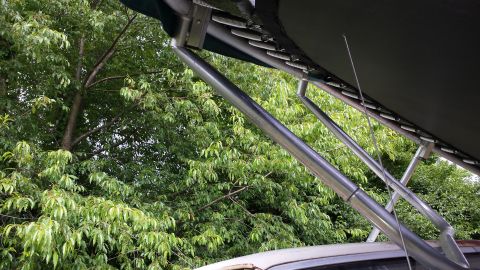 1979 Ford Bronco - A close-up view of an awning structure attached to a vehicle, with lush green foliage surrounding it.