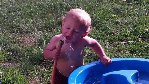 1979 Ford Bronco - A young child enjoys a refreshing drink from a garden hose on a sunny day.