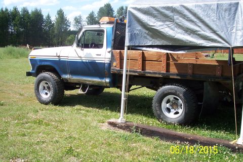 1973 Ford F-250 - Side view of a blue and white 1973 Ford F-250 flatbed truck with a wooden bed.