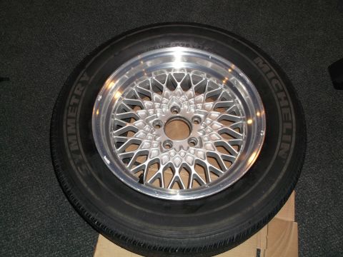 1999 Mercury Grand Marquis - A close-up of a tire and wheel assembly, likely aftermarket, is presented on a dark carpeted surface.