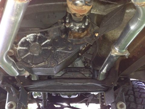 1979 Ford Bronco - Underside view of a vehicle's transfer case and dual exhaust pipes, showing signs of wear and tear.