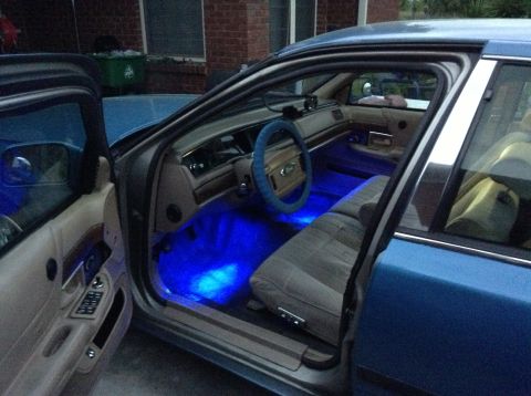 1994 Ford Crown Victoria - The interior of a blue sedan is illuminated by blue LED lights under the dashboard and seats.