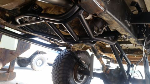 1988 Ford Bronco - Undercarriage view shows custom roll cage and suspension parts on a vehicle. Another vehicle is visible in the background.