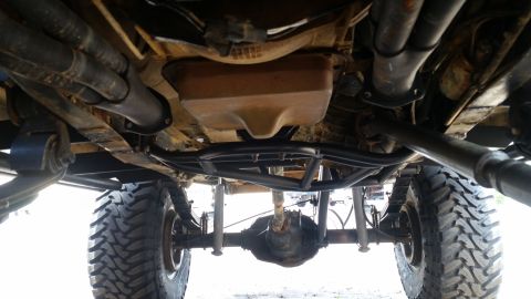 1988 Ford Bronco - The underside of a modified off-road vehicle reveals its heavy-duty suspension and drivetrain components.