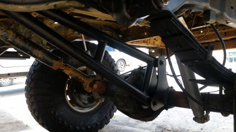 1988 Ford Bronco - A close-up shot of a vehicle's undercarriage, focusing on the suspension system, with another vehicle visible in the distance.
