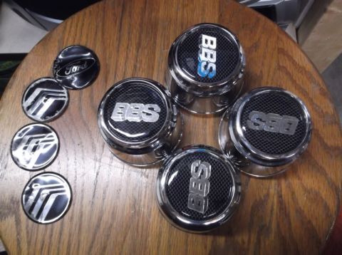 1999 Mercury Grand Marquis - Four BBS wheel center caps and three Mercury emblems are displayed on a wooden table.