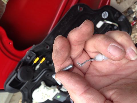 1979 Ford Bronco - Hand holding a broken door latch cable, with the interior door panel mechanism in the background.
