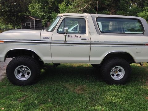 1979 Ford Bronco - A white 1978 Ford Bronco with a grey top and lifted suspension is parked on grass.