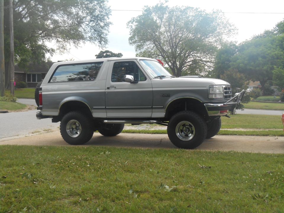 1994 Ford Bronco with lifted suspension and custom bumper, parked on a driveway.